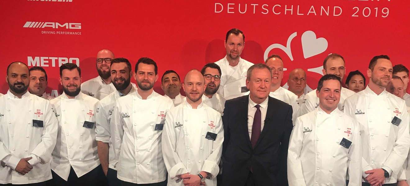 Lars Volbrecht steht rechts hinter Pascal Couasnon, CEO Michelin Food&Travel, auf der Bühne in Berlin.