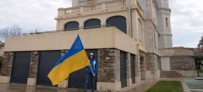 Ein Friedensaktivist schwenkt die Ukraine-Flagge vor der Villa des Oligarchen in Biarritz